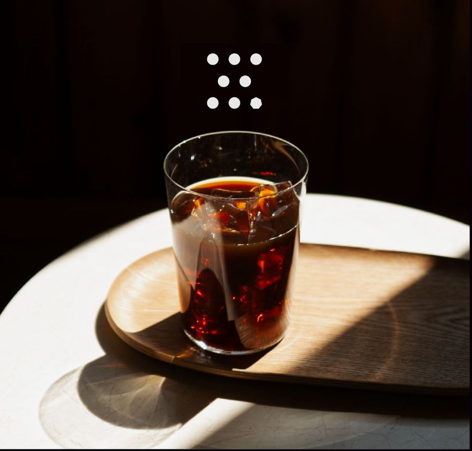 Iced coffee in a glass on a wooden tray, in soft light