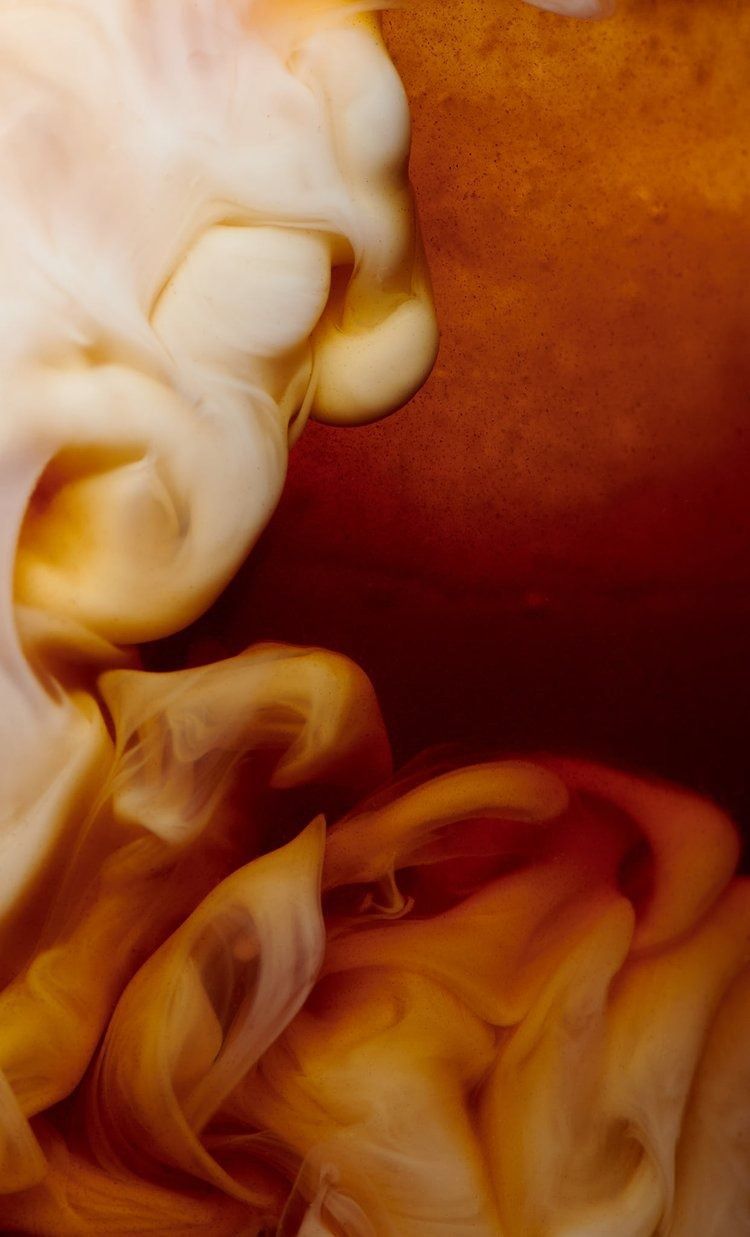 Cream swirling into dark coffee